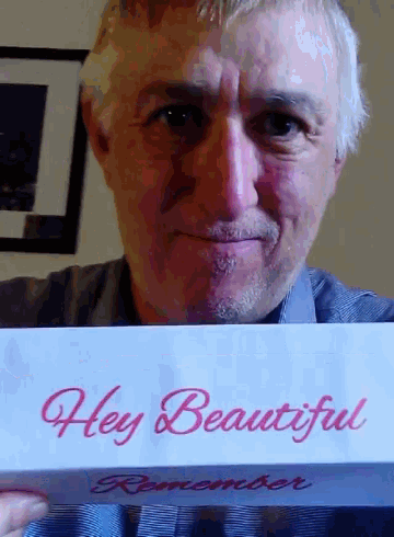 a man holding a sign that says hey beautiful remember