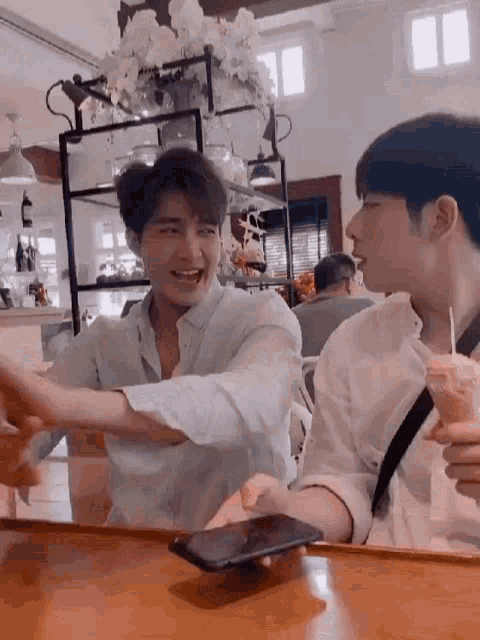 two men are sitting at a table with their arms outstretched in a restaurant .