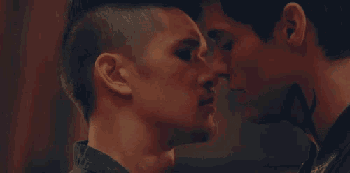 two men are standing next to each other and looking at each other with their eyes closed .