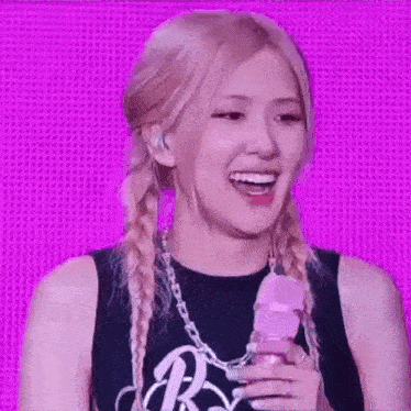 a close up of a woman holding a microphone and smiling on a stage .