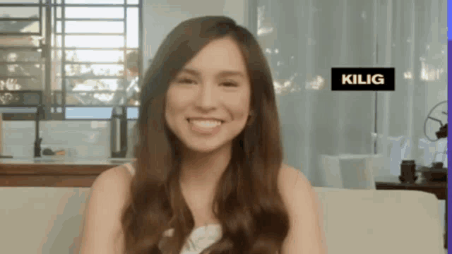 a woman sits on a couch with a sign that says kilig