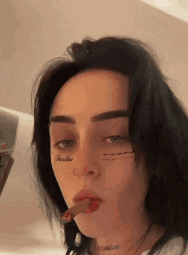 a woman with a tattoo on her face that says fearless is smoking a cigar