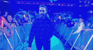 a man with long hair and a beard is walking on a stage .