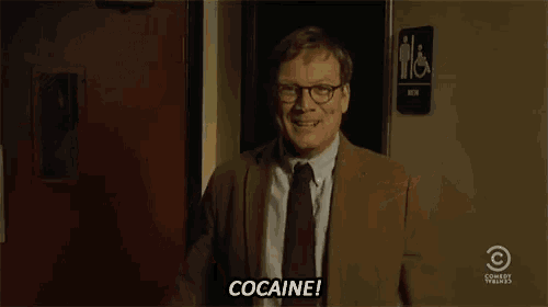 a man in a suit and tie is laughing and saying cocaine .