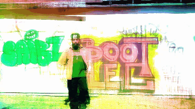 a man stands in front of a wall with graffiti on it that says boot hell