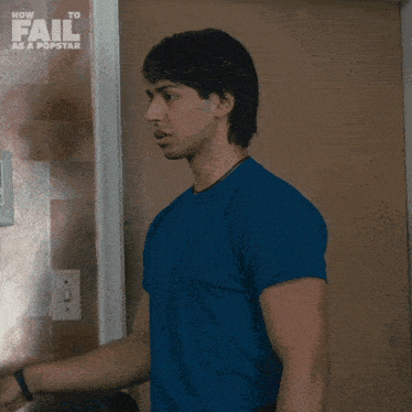 a man in a blue shirt is standing in front of a sign that says how to fail as a pop star