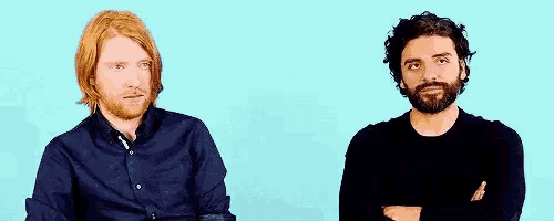 two men are sitting next to each other with their arms crossed and looking at each other .