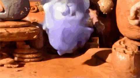a purple object is sitting on top of a pile of rocks on a dirt surface .
