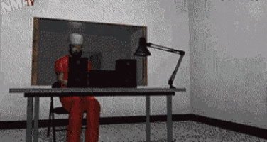 a man in a prison uniform is sitting at a desk using a laptop computer