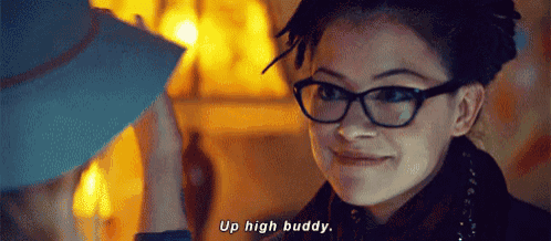 a woman wearing glasses is smiling and saying " up high buddy "
