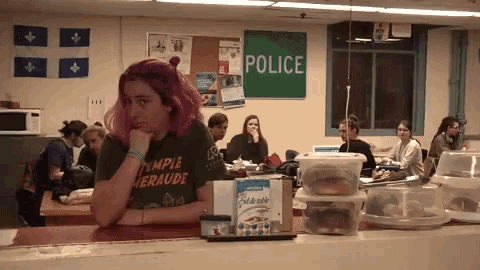 a woman sits at a table in front of a green sign that says police