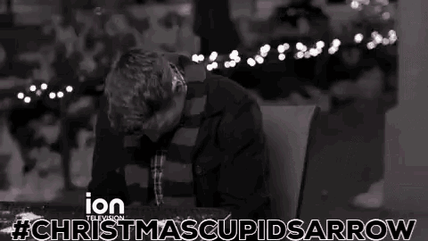 a man is sitting at a table with a cup of coffee in front of christmas lights .