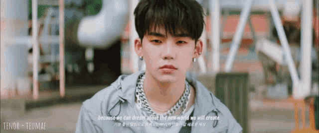 a young man wearing a necklace and earrings is looking at the camera with a quote behind him .