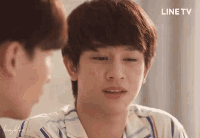 a young man is looking at another young man while sitting next to each other .