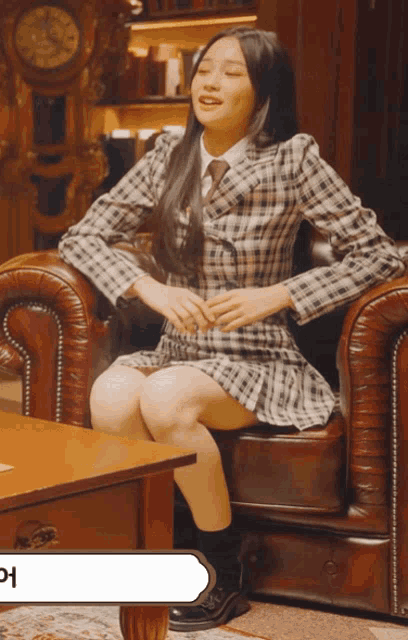 a woman in a plaid dress is sitting on a leather chair