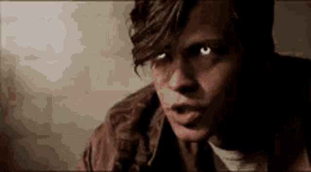 a close up of a young man 's face with glowing eyes looking at the camera .
