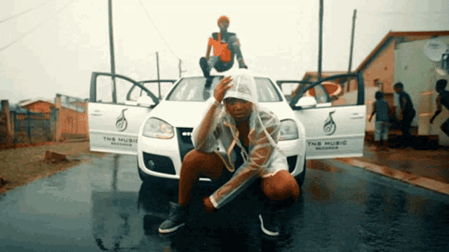 a man kneeling in front of a tns music car