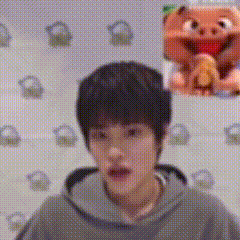 a close up of a person 's face with a stuffed animal in the background