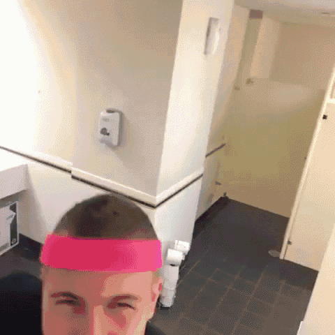 a man wearing a pink headband in a public restroom