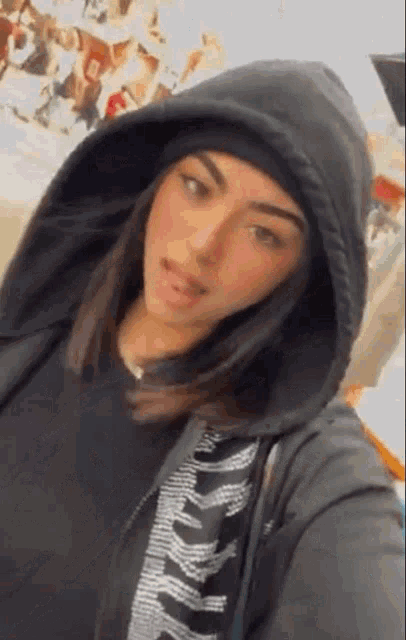 a woman is wearing a black hoodie and a black hat