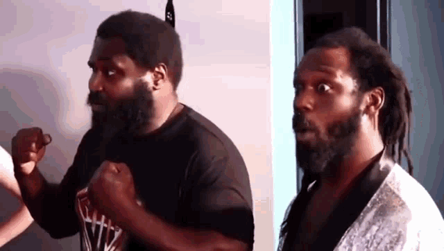 two men with beard and dreadlocks are standing next to each other .