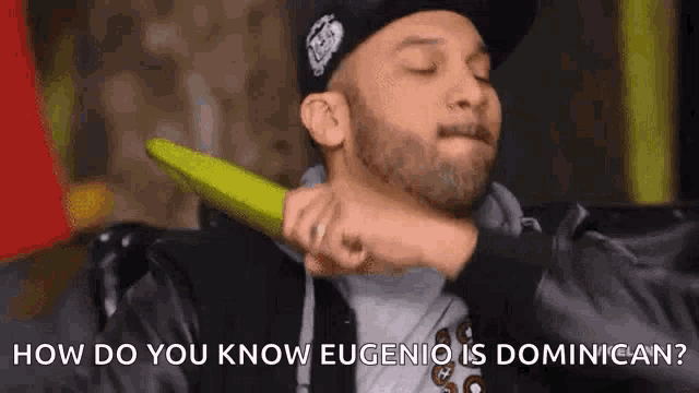 a man in a hat is holding a green object in his hand and says how do you know eugenio is dominican .