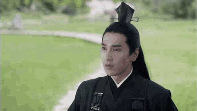 a man with long black hair wearing a black kimono and a black hat