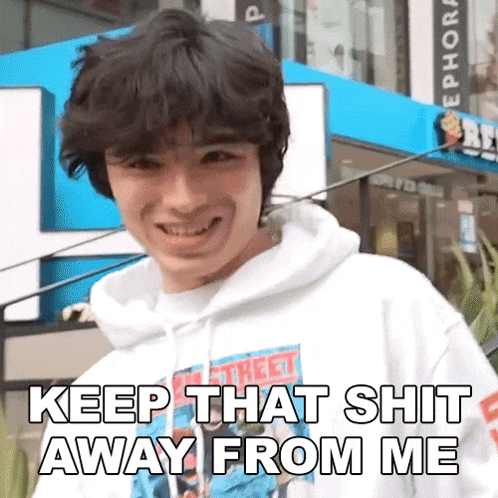 a young man wearing a white hoodie is smiling and says keep that shit away from me
