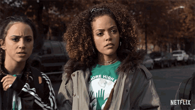 a girl wearing a green shirt that says more high is standing next to another girl