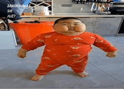 a baby in a red outfit is standing on a tiled floor .