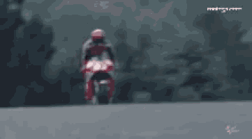 a man is riding a red and black motorcycle on a road ..
