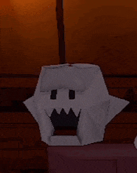a white origami ghost is sitting on a wooden shelf .