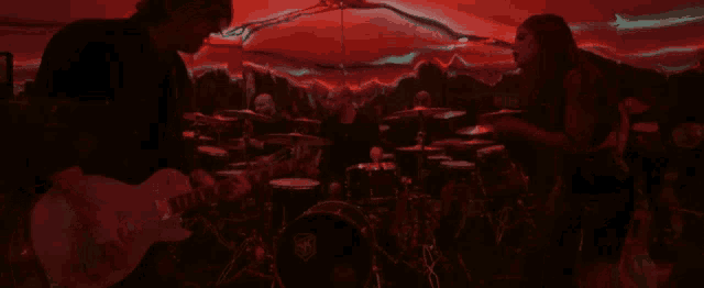a man playing a guitar in front of a drum set that says ' fender ' on it