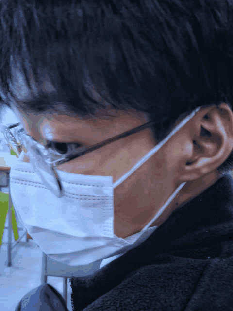a man wearing a face mask and glasses looks down