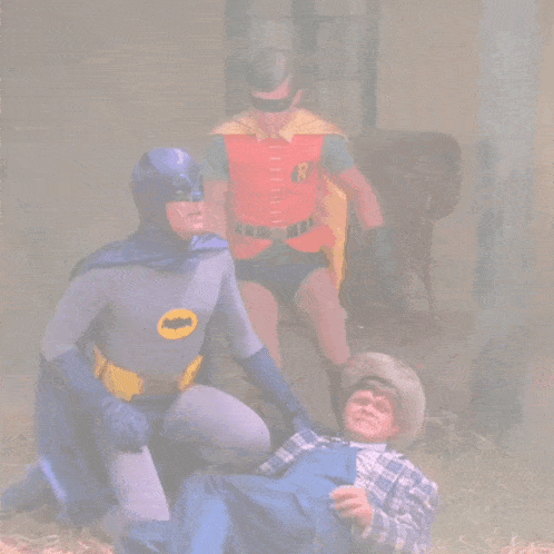 a man in a cowboy hat is laying on the ground while batman and robin watch