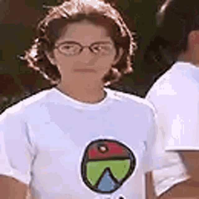 a young girl wearing glasses and a white t-shirt with a colorful circle on it .