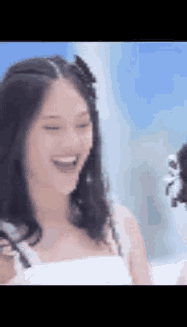 a woman in a white dress is laughing while standing next to another woman .