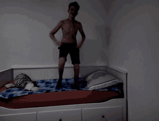 a shirtless man is standing on a bed pointing