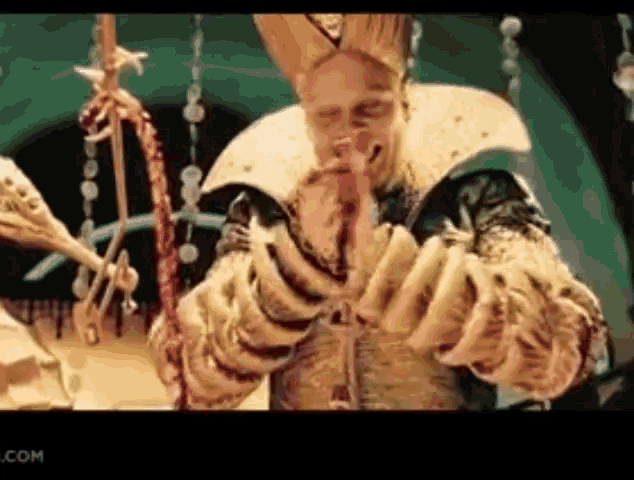 a man in a costume with a crown on his head is praying with his hands together .