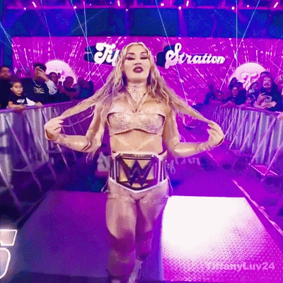 a woman in a wrestling outfit is walking down a purple aisle with the word stratton behind her