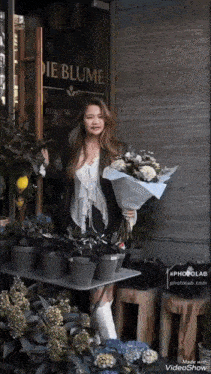 a woman holding a bouquet of flowers standing in front of a store called die blume