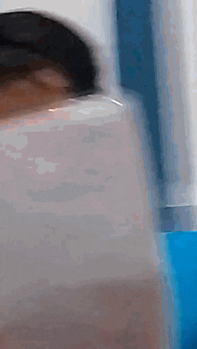 a blurry picture of a person 's face with a blue curtain in the background