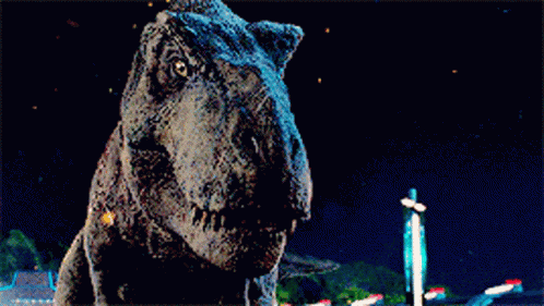 a t-rex dinosaur is looking at the camera with a dark background