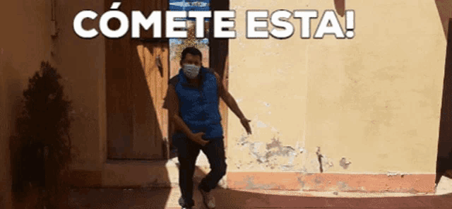 a man wearing a mask is dancing in front of a wall that says comete esta on it