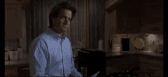 a man in a blue shirt is standing in the kitchen