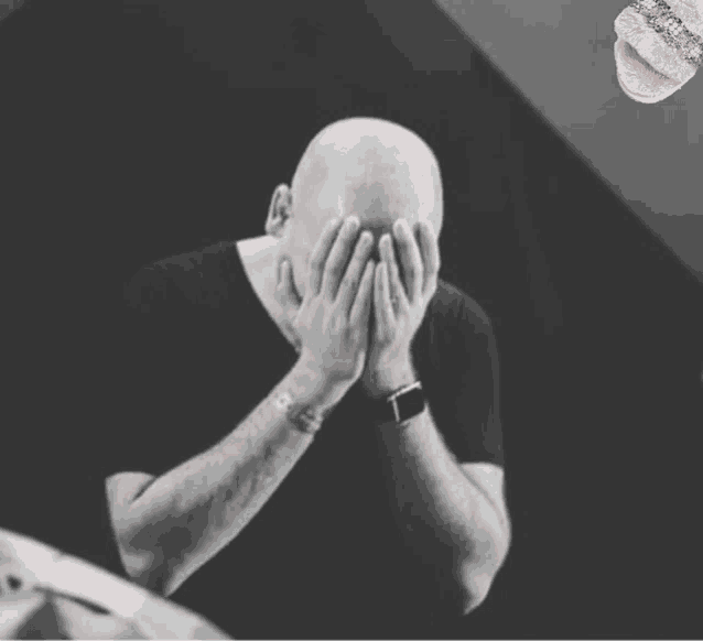 a man is covering his face with his hands while wearing a watch .