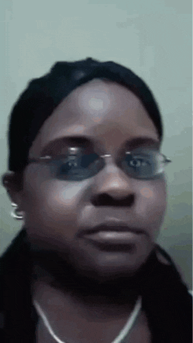 a woman wearing glasses and a black hat is making a funny face .