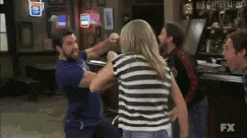 a man and a woman are fighting in front of a bar that says fx
