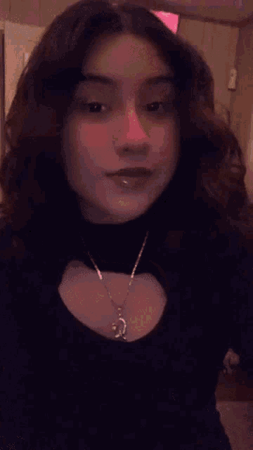 a girl wearing a black shirt and a necklace with a pendant