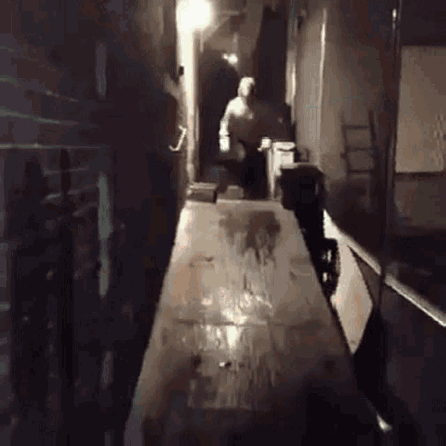 a person is walking down a dark hallway with a table in the foreground .
